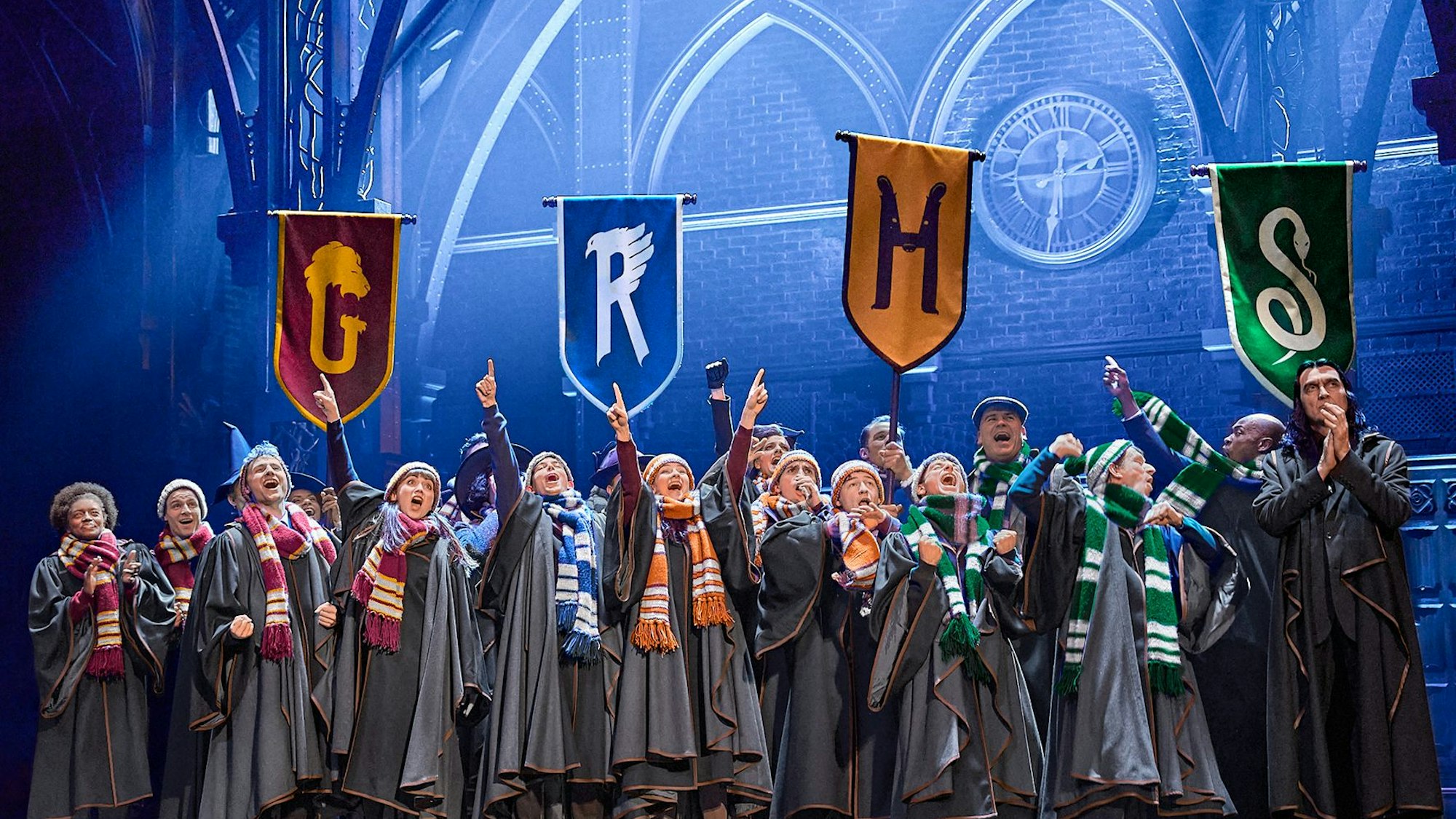 Kinder in Umhängen stehen auf einer Bühne.