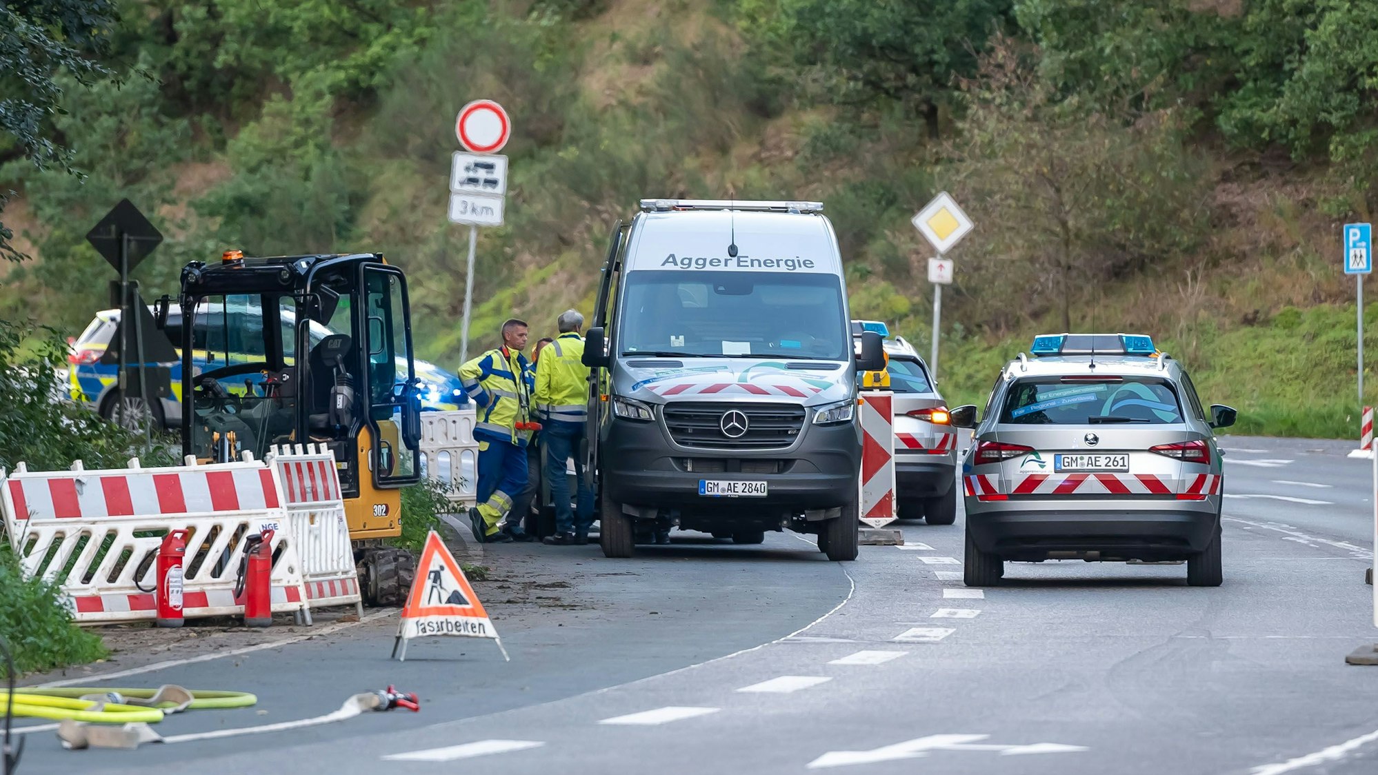 Einsatzwagen der Aggerenergie stehen neben dem Kleinbagger, der die Leitung getroffen hat.