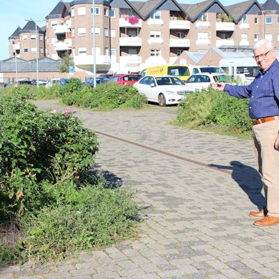 Hans-Peter Nußbaum steht auf dem Whitnash-Platz und zeigt auf Sträucher.