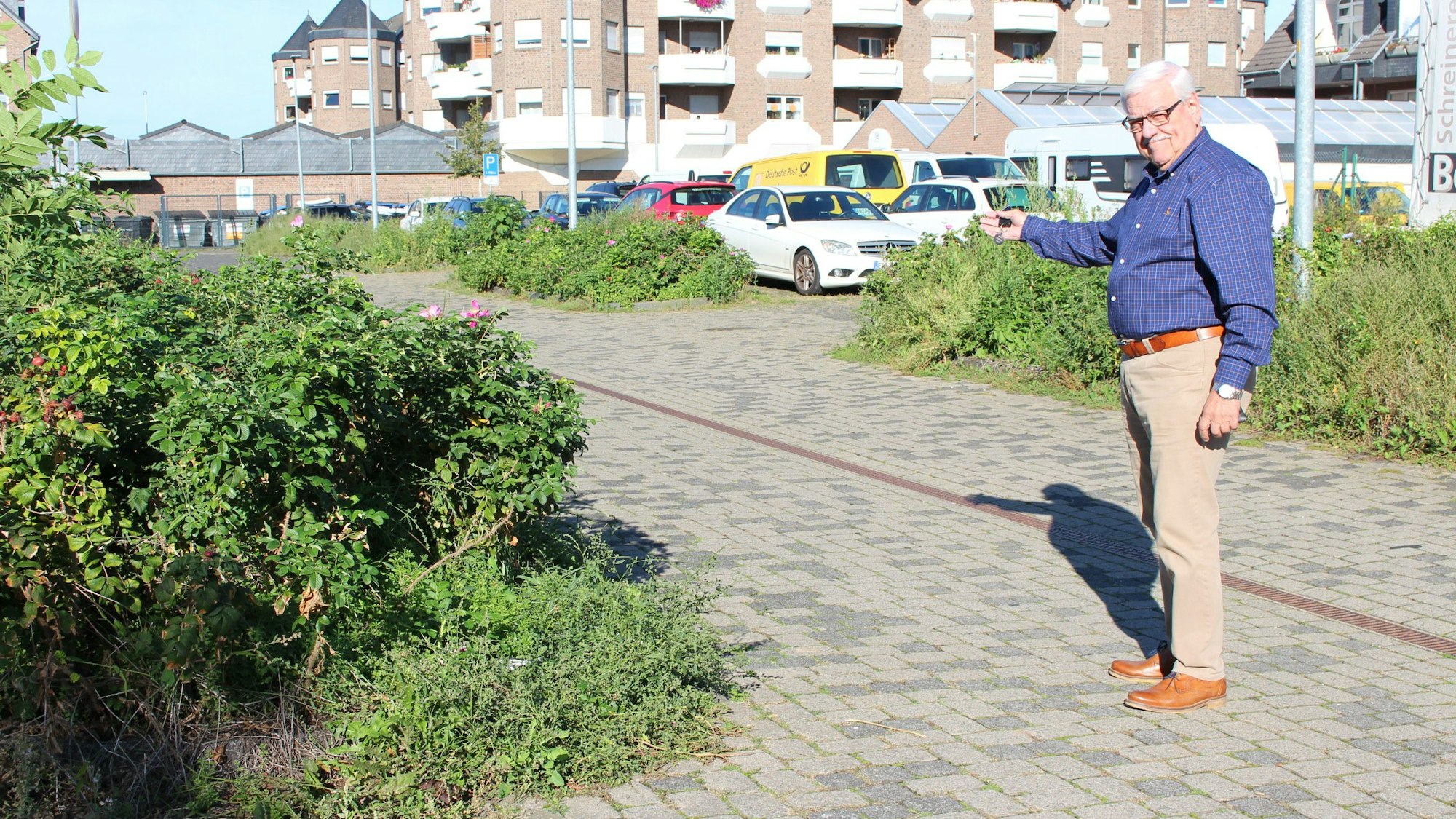 Hans-Peter Nußbaum steht auf dem Whitnash-Platz und zeigt auf Sträucher.