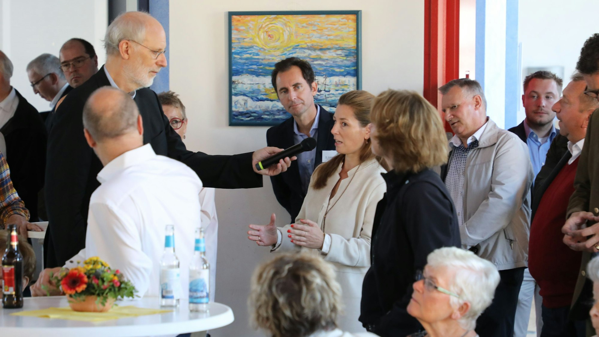 Weihbischof Ansgar Puff steht mit einem Mikrofon im Publikum und interviewt eine Frau.