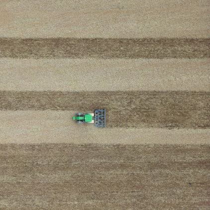 Eine Egge zieht dieser Landwirt hinter seinem Traktor über ein Feld.