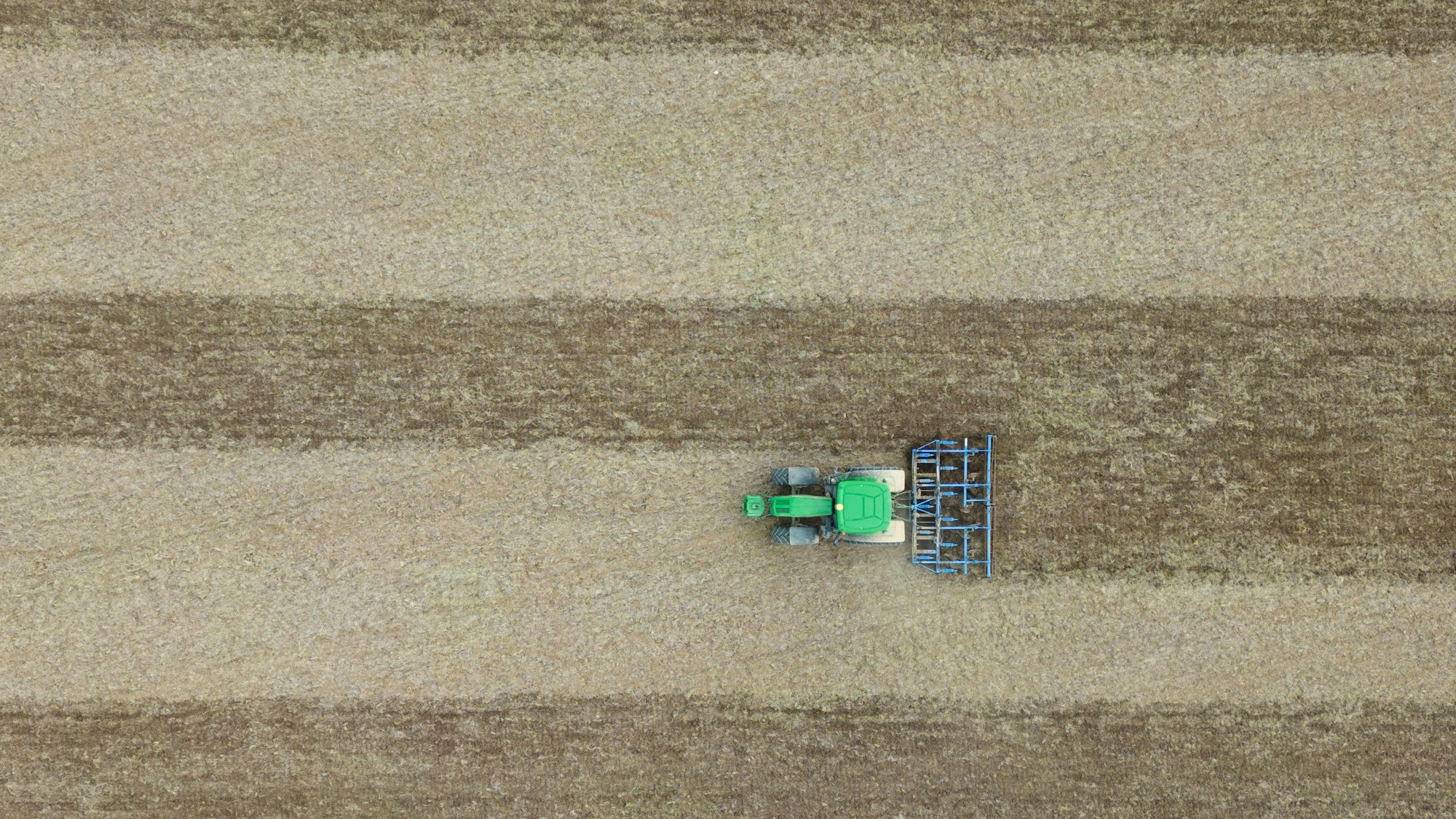 Eine Egge zieht dieser Landwirt hinter seinem Traktor über ein Feld.