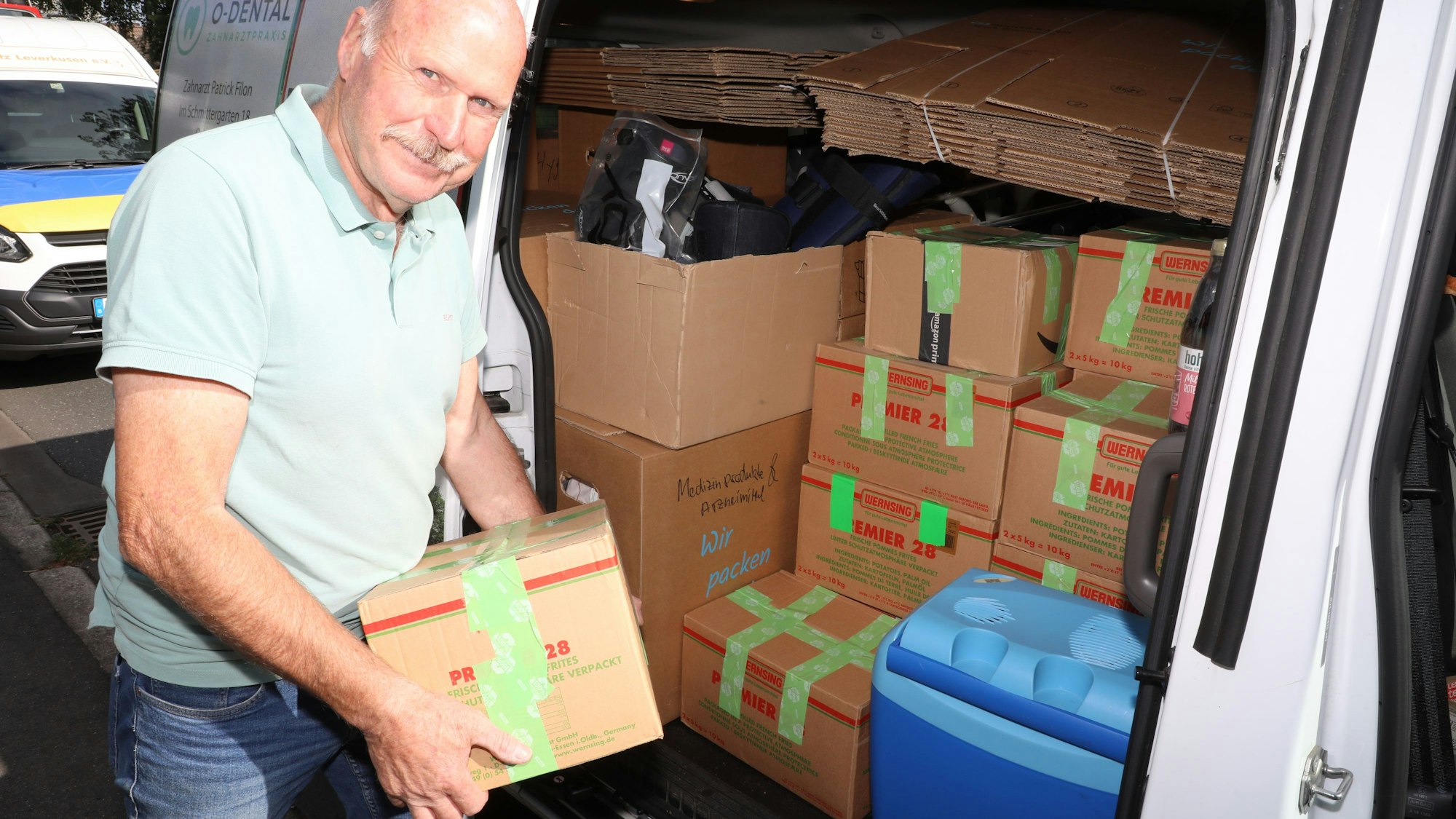 Ein Mann lädt einen Karton in einen Lieferwagen ein.