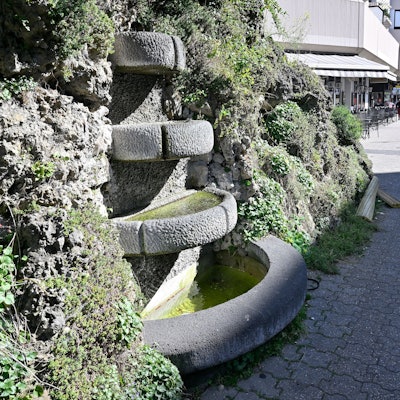 Man sieht den Brunnen mit seinen vier Becken und dem Muschelkalk drumherum.
