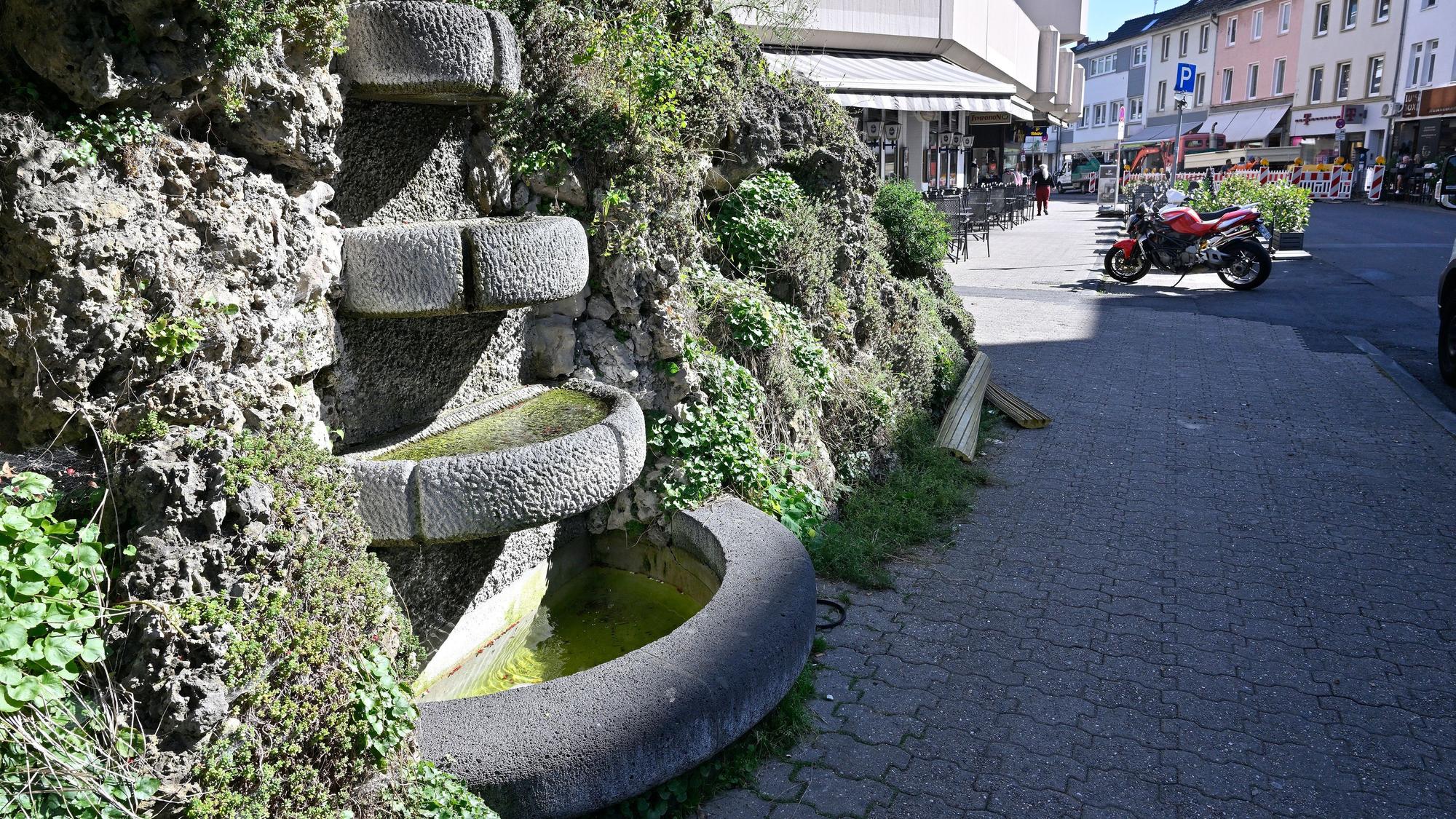 Man sieht den Brunnen mit seinen vier Becken und dem Muschelkalk drumherum.