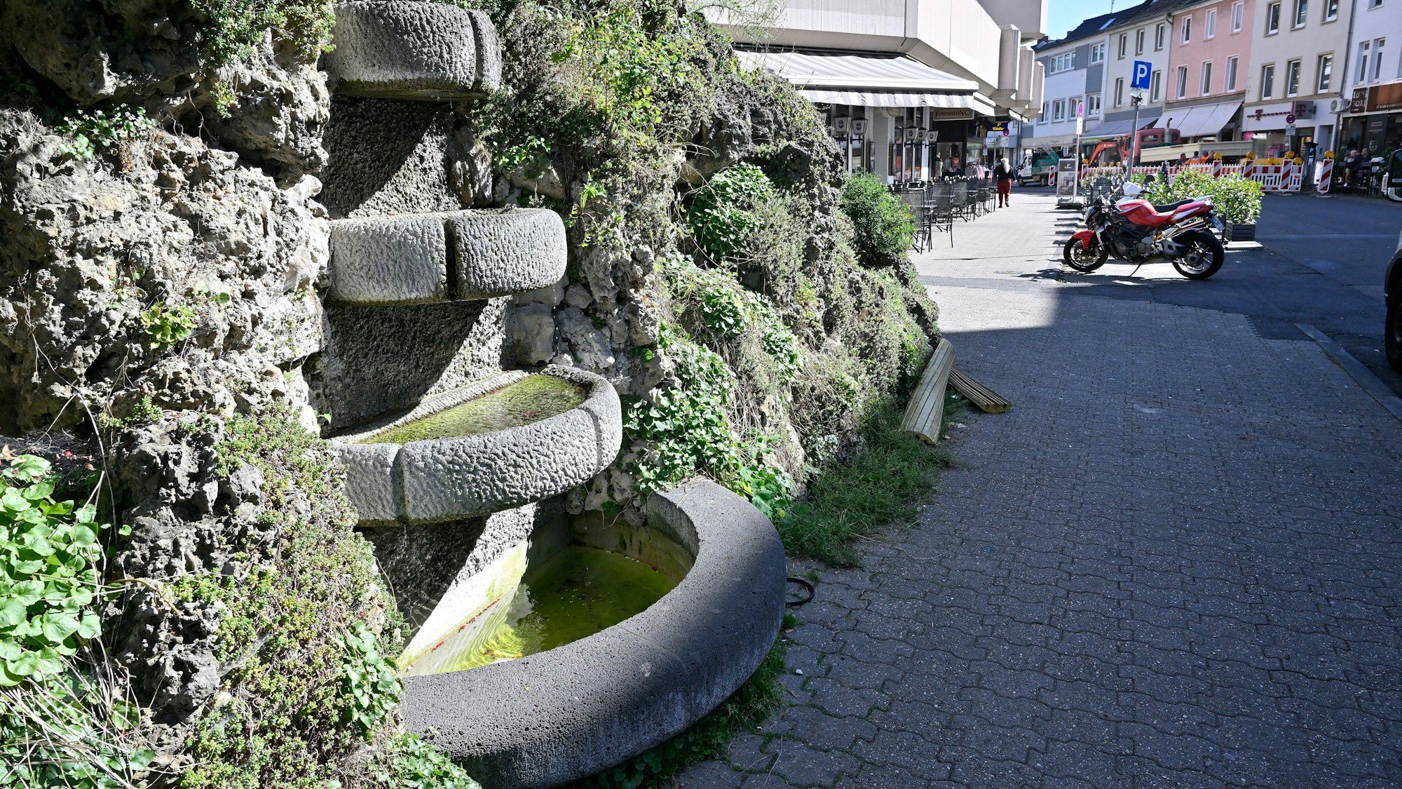 Man sieht den Brunnen mit seinen vier Becken und dem Muschelkalk drumherum.