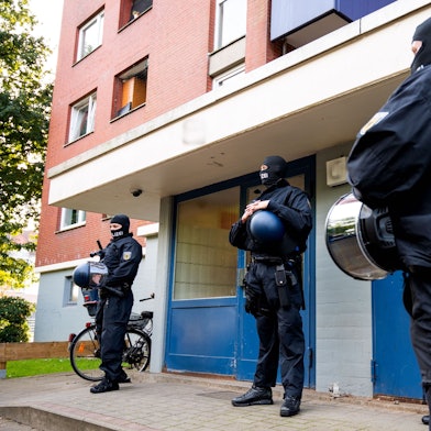 Bundespolizisten sind vor einem Wohnhaus bei einer Razzia im Einsatz.