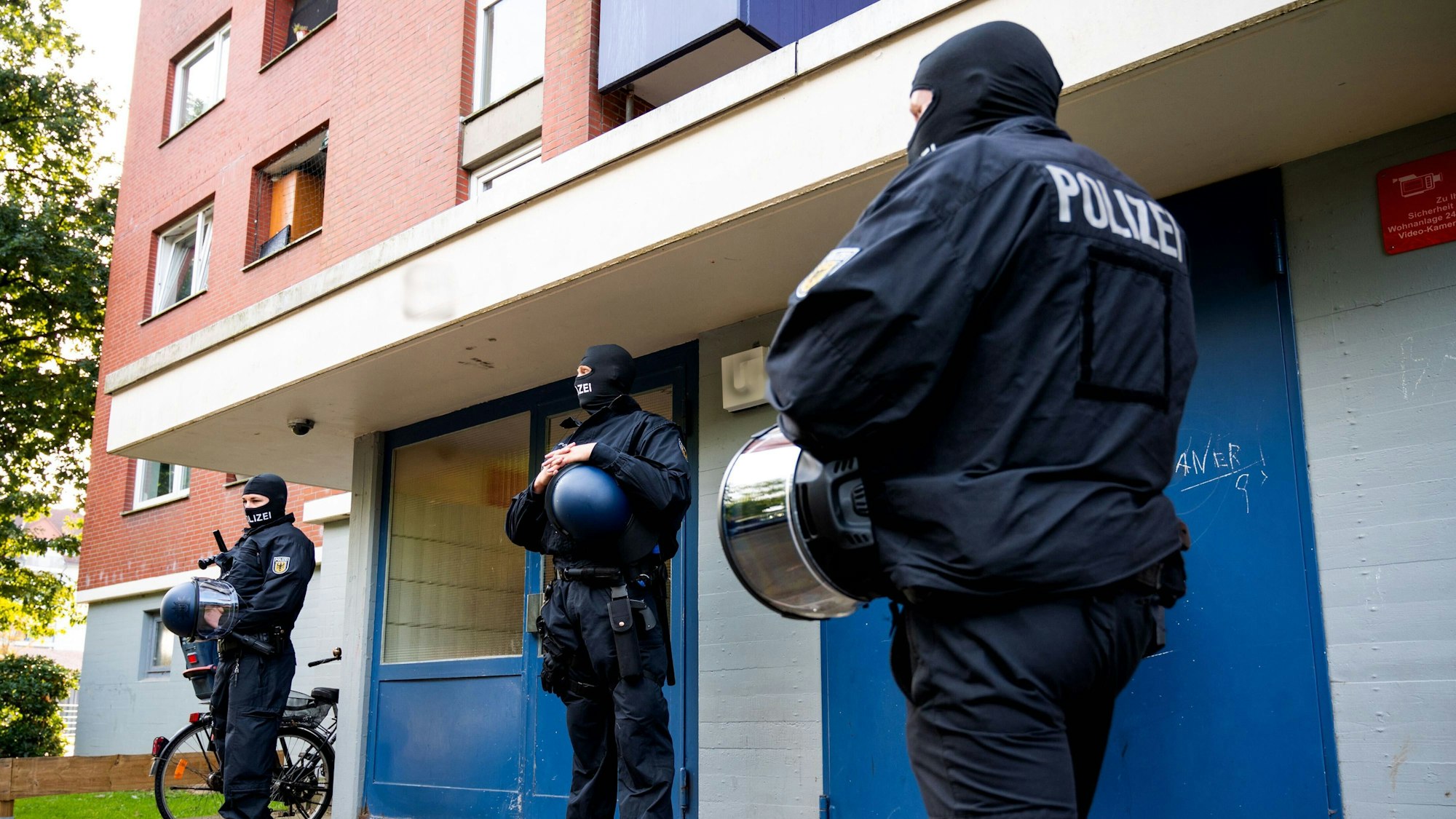Bundespolizisten sind vor einem Wohnhaus bei einer Razzia im Einsatz.