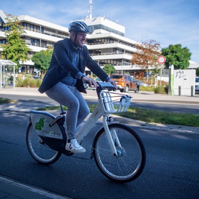 Landrat Markus Ramers radelt mit seinem E-Bike an der Kreisverwaltung in Euskirchen vorbei.