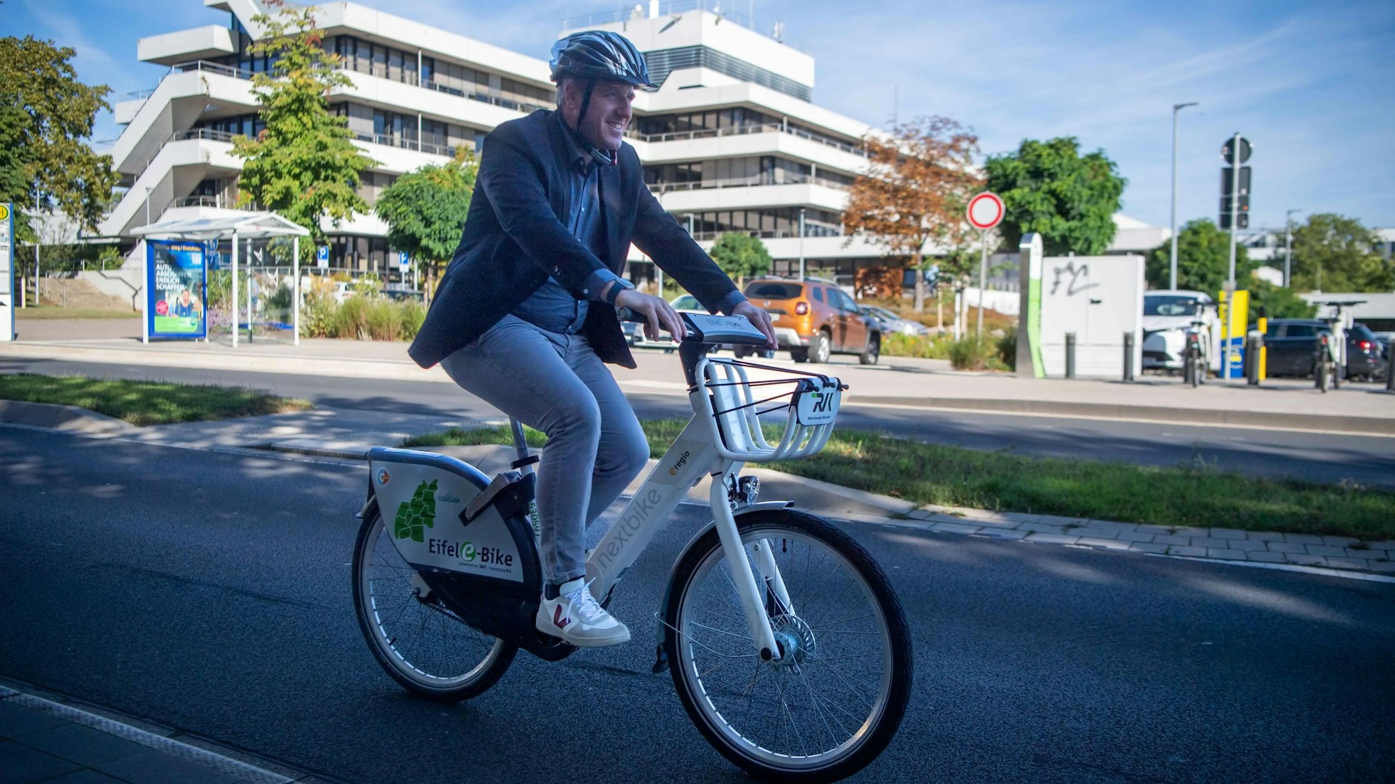 Landrat Markus Ramers radelt mit seinem E-Bike an der Kreisverwaltung in Euskirchen vorbei.