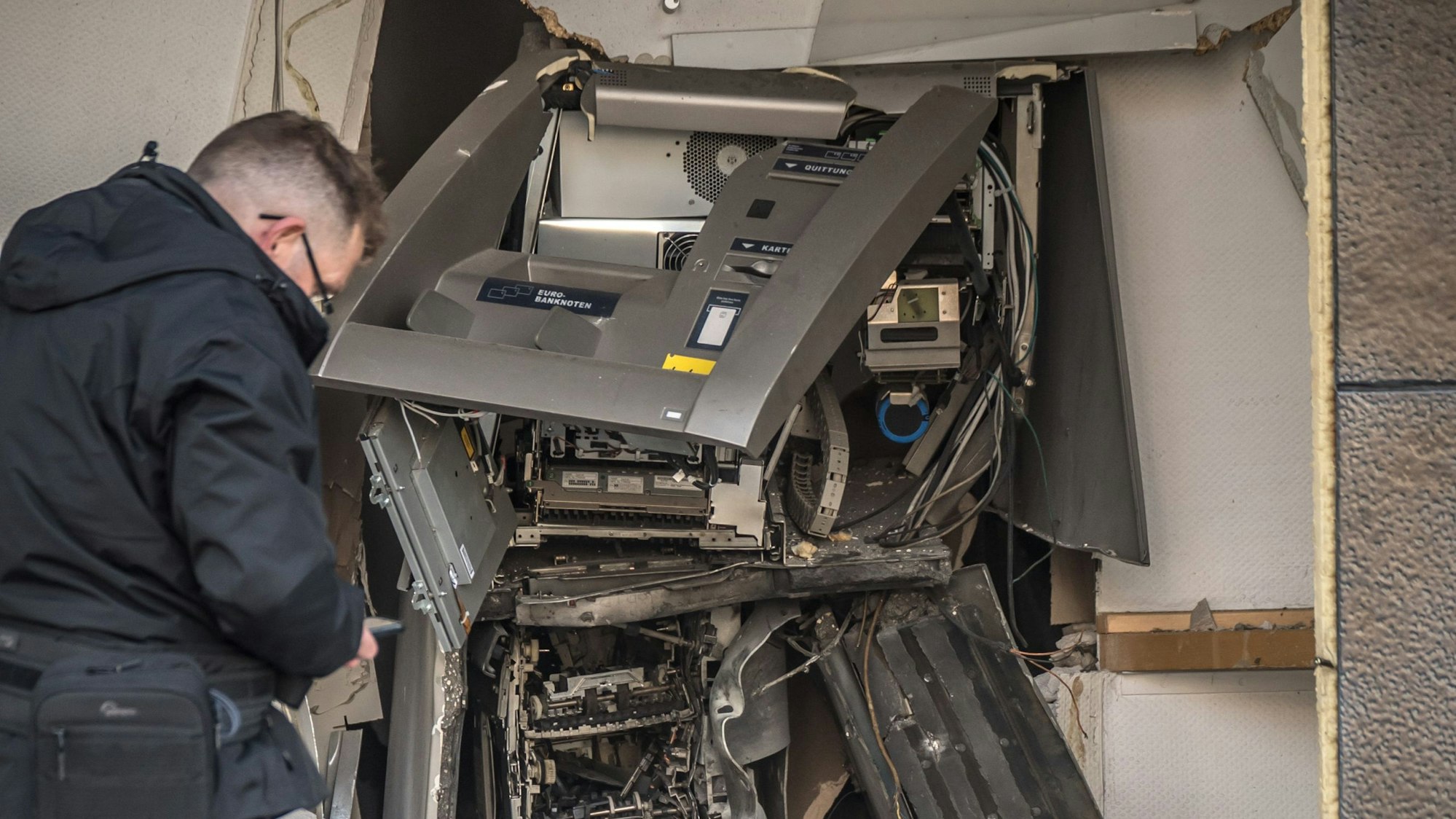 Ein aufgesprengter Automat, davor ein Mann