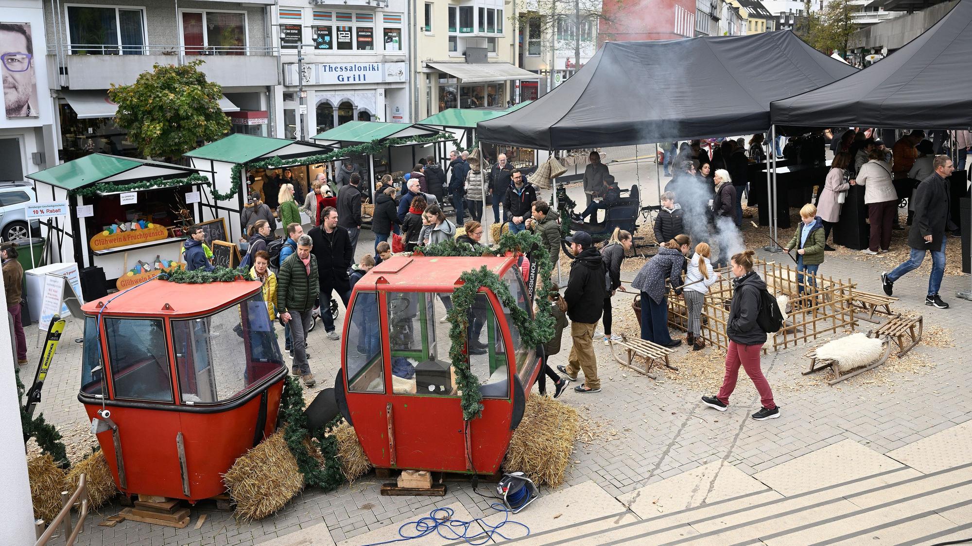 Zu sehen sind zwei rote Gondeln, davor laufen Besucher des Festes entlang.