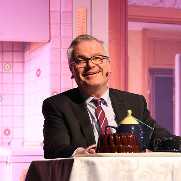 Kabarettist Jürgen B. Hausmann sitzt an einem Tisch.