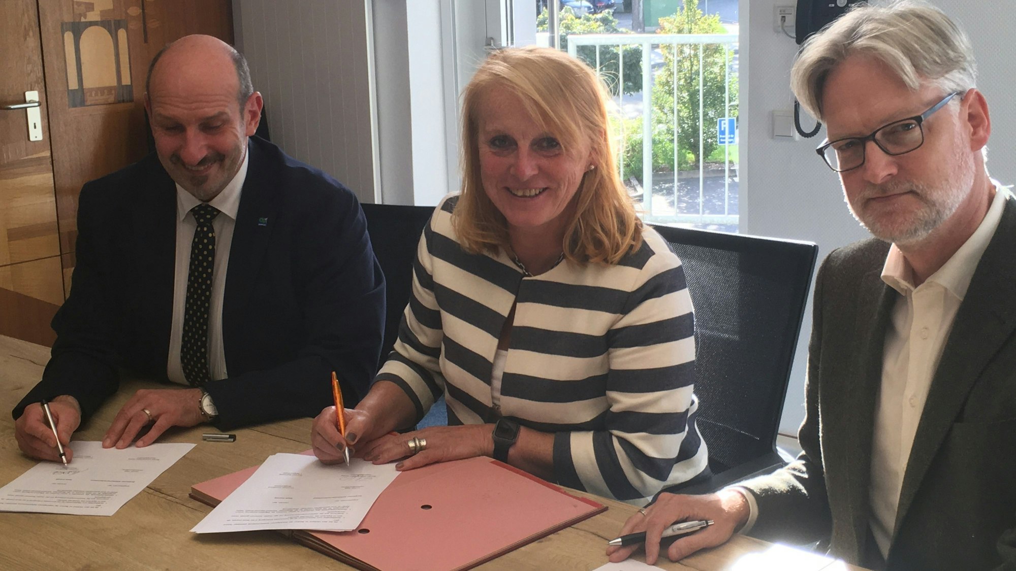 l. Bürgermeister Christoph Nicodemus, BAV-Geschäftsführerin Monika Lichtinghagen-Wirths, Erster Beigeordneter Thorsten Steinwartz sitzen nebeneinander vor Unterlagen.