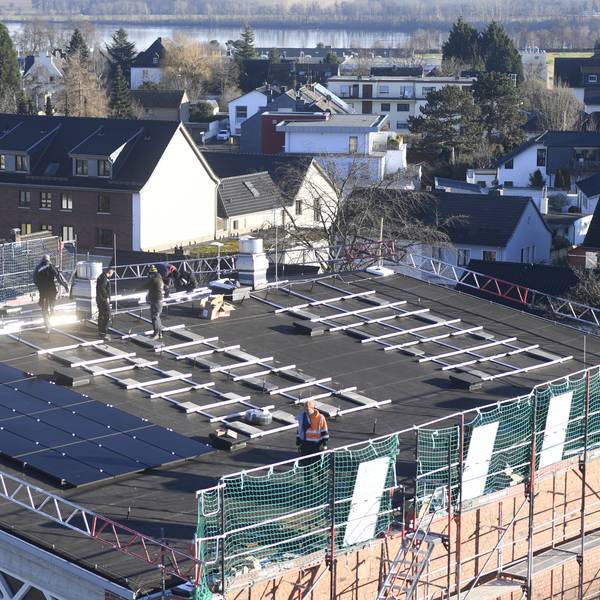 Bauarbeiter installieren Solarmodule auf dem Dach einer Kirche.