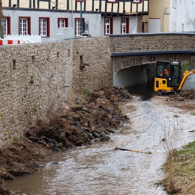 Ein Bagger steht in der Erft in Bad Münstereifel. Zu sehen sind auch die wieder aufgebauten Erftmauern.