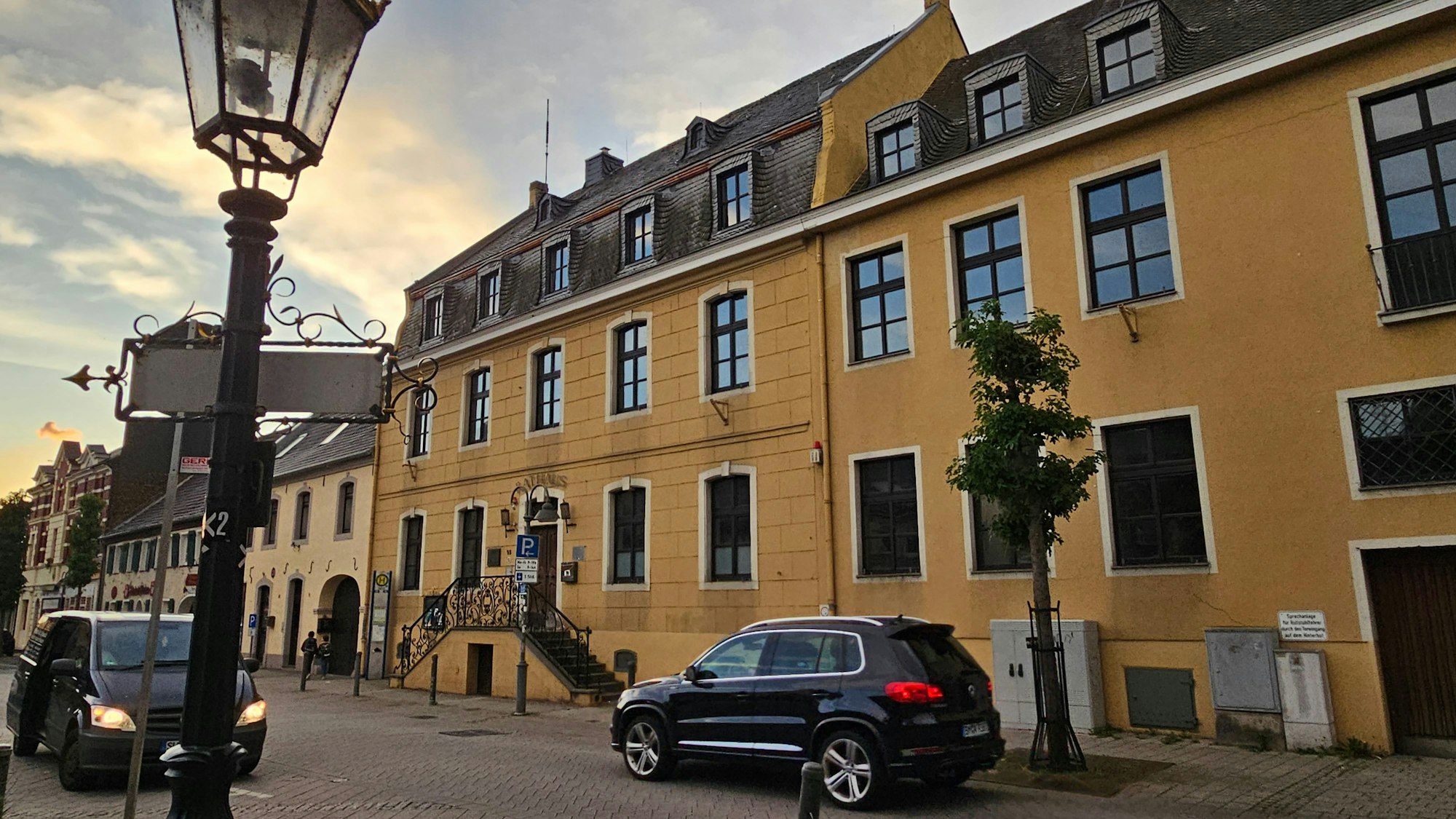 An einem prächtigen gelben alten Haus fahren Autos vorbei.
