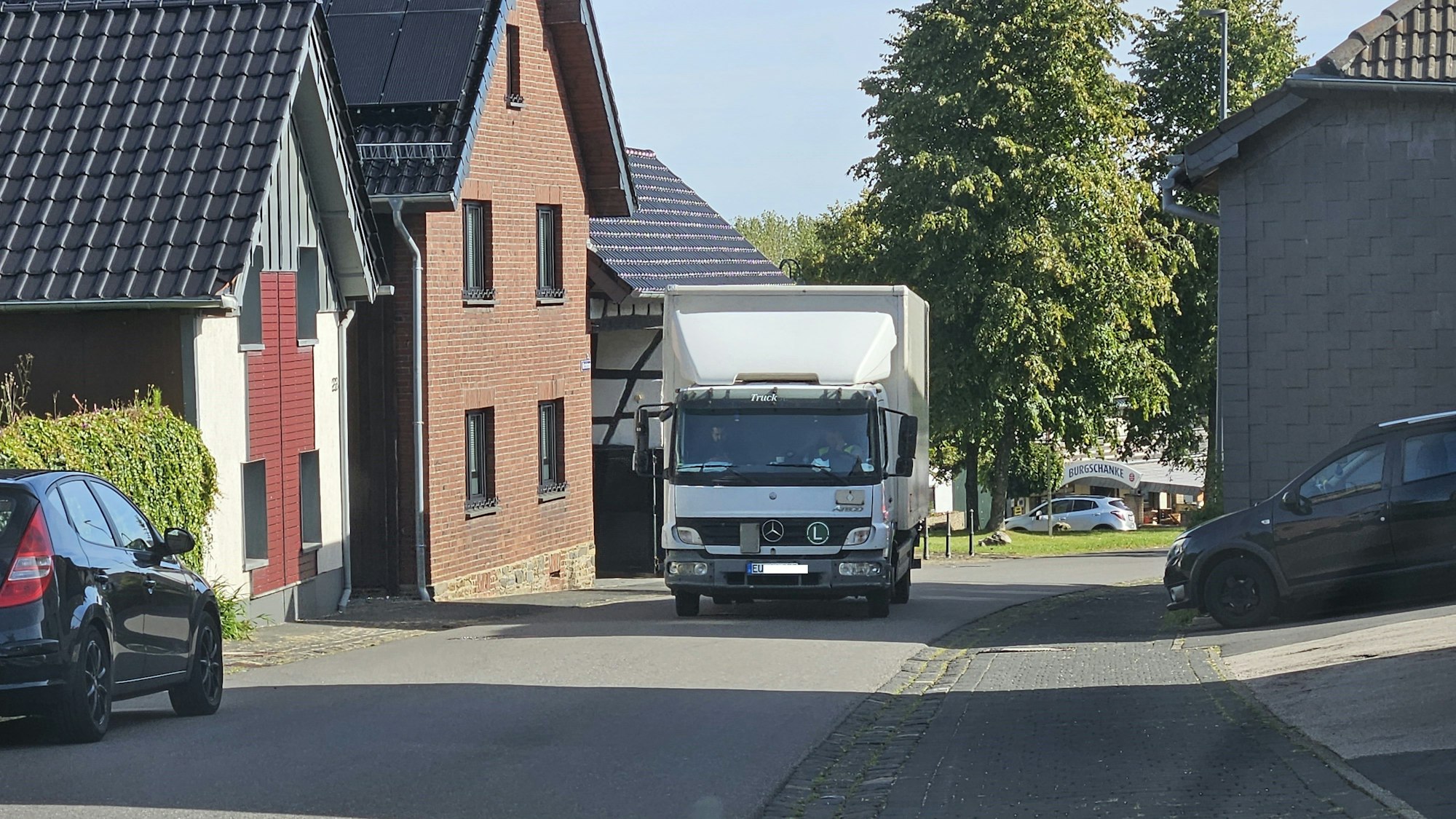 Ein Lkw fährt auf der engen Ortsdurchfahrt in Dreiborn an Häusern entlang.