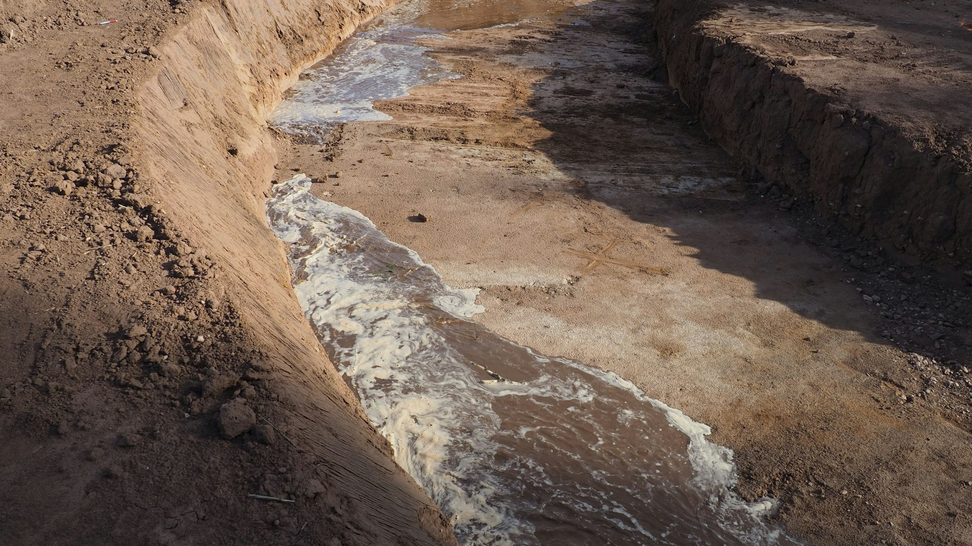 Wasser fließt aus zwei Richtungen durch einen Graben.