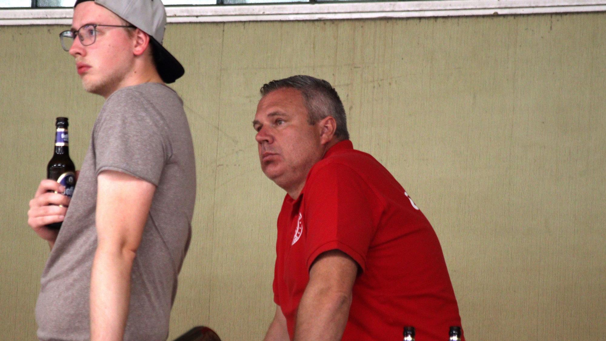 Basketballtrainer Marcus Görner sitzt mit missmutigem Gesicht auf der Tribüne und schaut das Spiel seiner Mannschaft an.