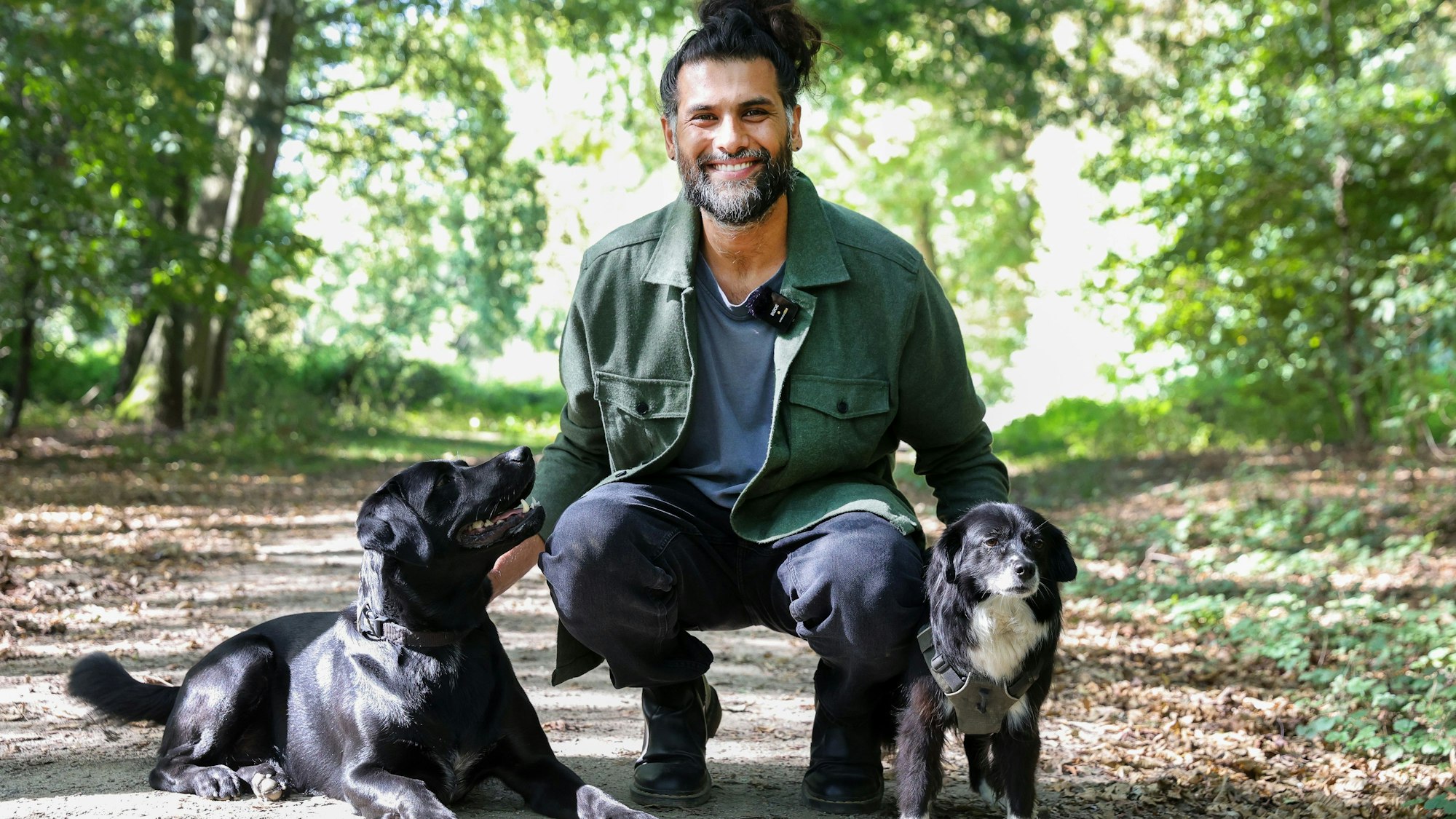 Hunde-Verhaltenstherapeut Masih Samin mit zwei hHunden im Wald.