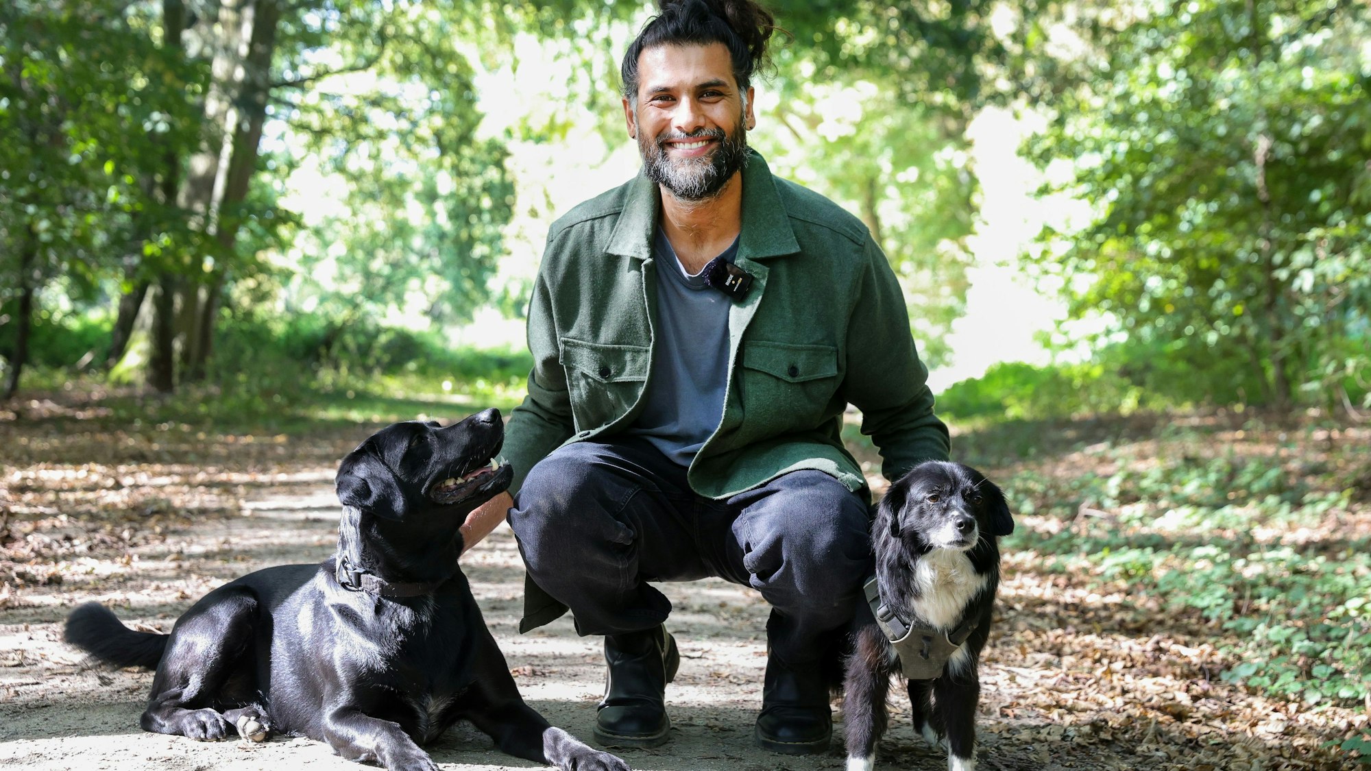 Hunde-Verhaltenstherapeut Masih Samin mit zwei Hunden auf einem Waldweg.