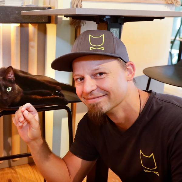 Michael Guddat, Tierpsychologe, Katzensitter und Katzenexperte, mit einer schwarzen Katze im Café Katzentempel in der Kölner Severinstrasse.