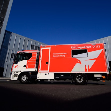 Das Fahrzeug der Feuerwehr steht auf einem Parkplatz vor einem Feuerwehrgebäude.