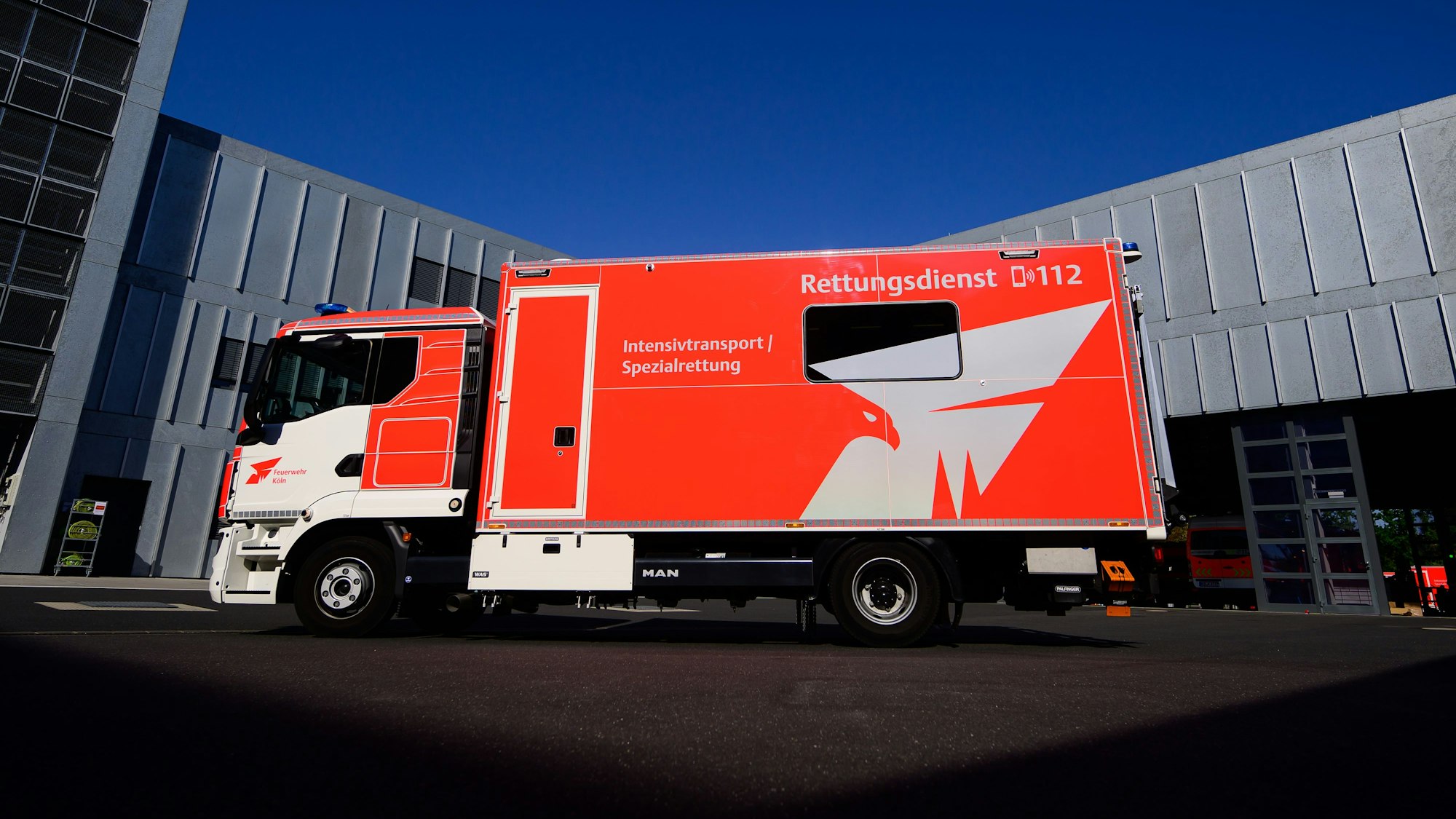 Das Fahrzeug der Feuerwehr steht auf einem Parkplatz vor einem Feuerwehrgebäude.