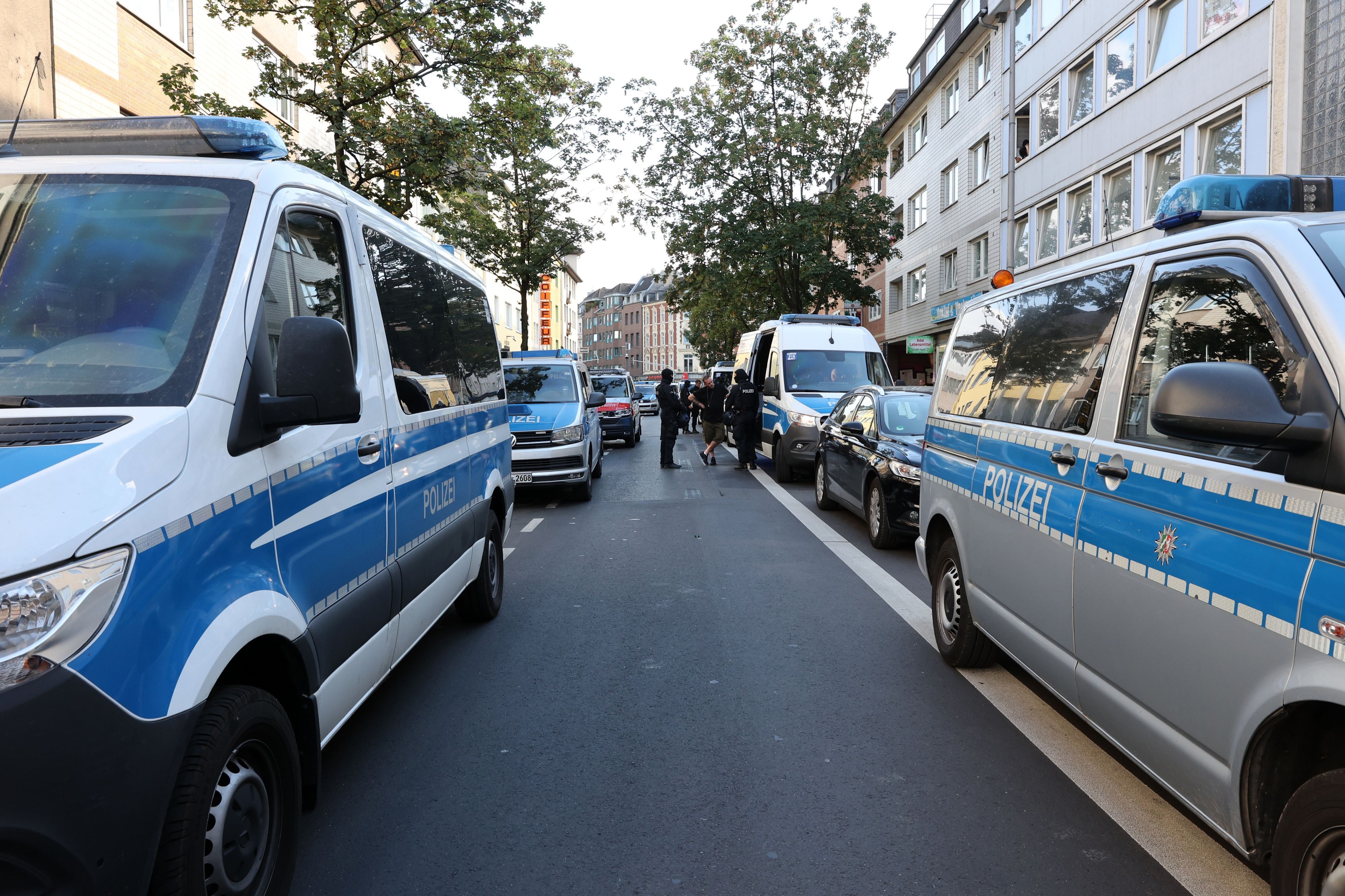 Einsatzfahrzeuge der Polizei säumen beide Seiten einer Straße.