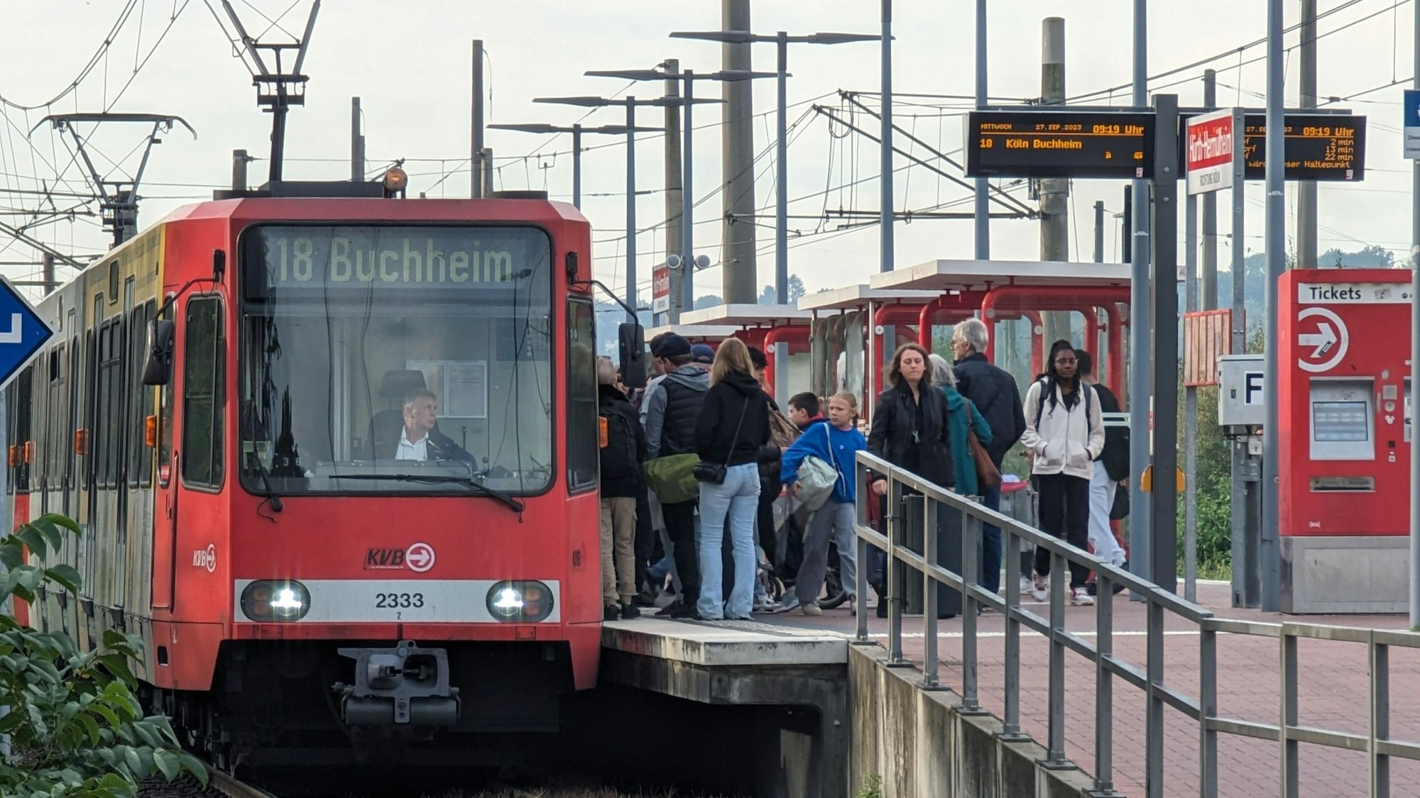 Eine Straßenbahn steht am bevölkerten Bahnsteig in Hermülheim.