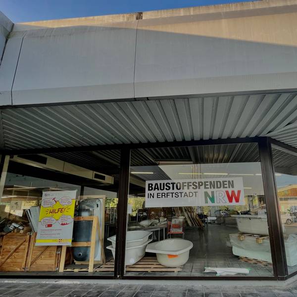 Das Bild zeigt ein Gebäude mit einem Schaufenster, in dem Sanitärwaren zu sehen sind.
