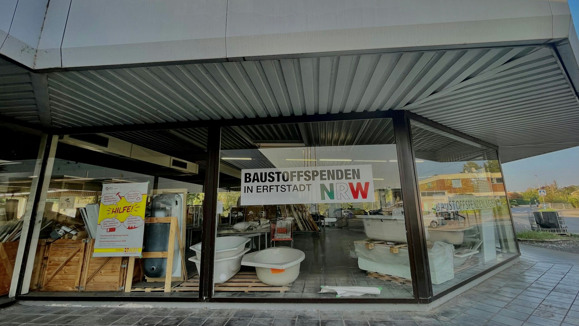 Das Bild zeigt ein Gebäude mit einem Schaufenster, in dem Sanitärwaren zu sehen sind.