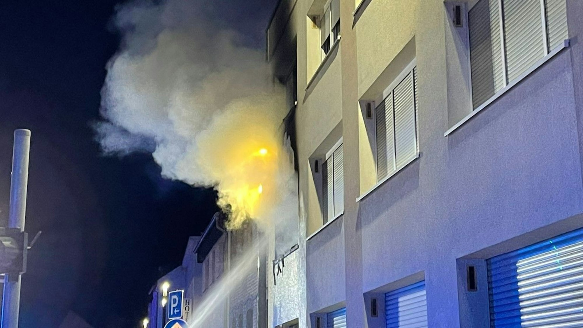Flammen schlagen aus einem Fenster im ersten Obergeschosses eine Mehrfamilienhauses in Bergheim.