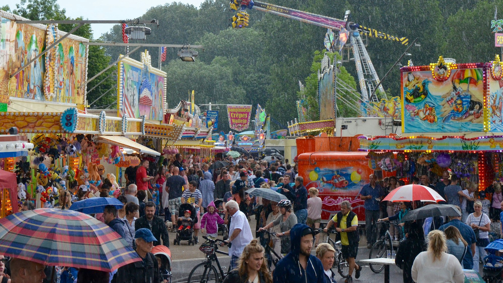 Beim Strandfest am Mondorfer Rheinufer drängen sich die Besucherinnen und Besucher zwischen Kirmesbuden und Fahrgeschäften.