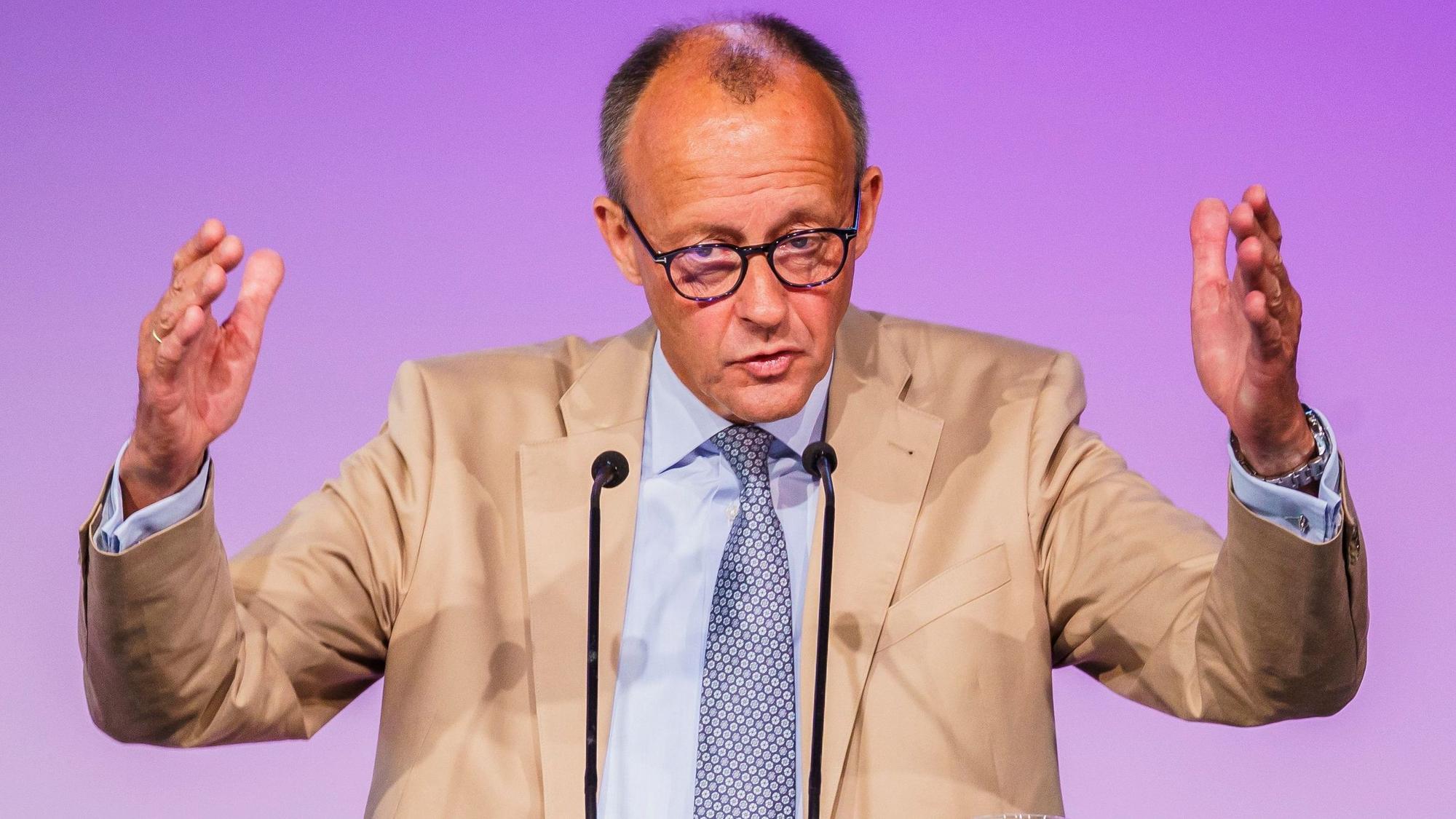 Der CDU-Vorsitzende Friedrich Merz hebt bei einer Rede beide Arme nach oben und gestikuliert vor einem Rednerpult.