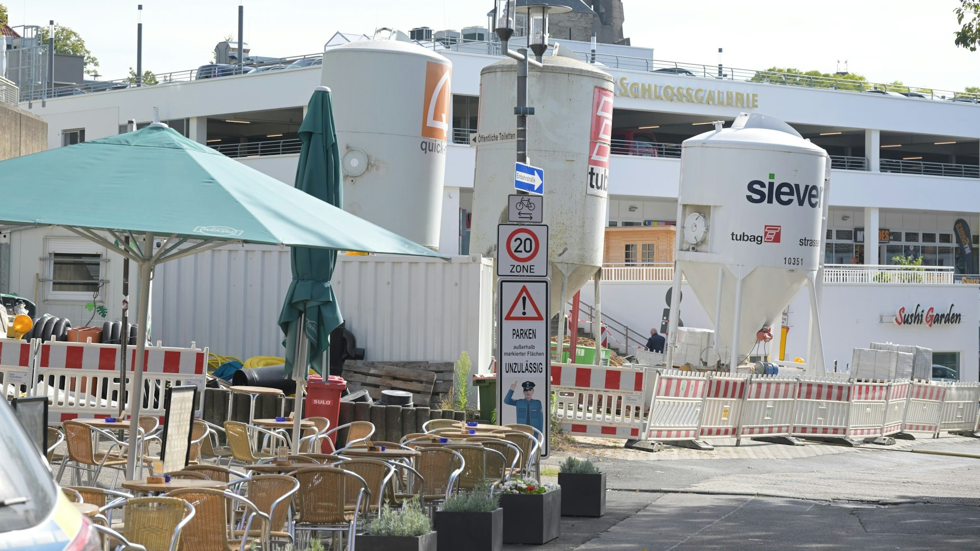 Tische und Stühle stehen auf dem Platz vor der Schlosstreppe. Im Hintergrund stehen Silos und Bauzäune.