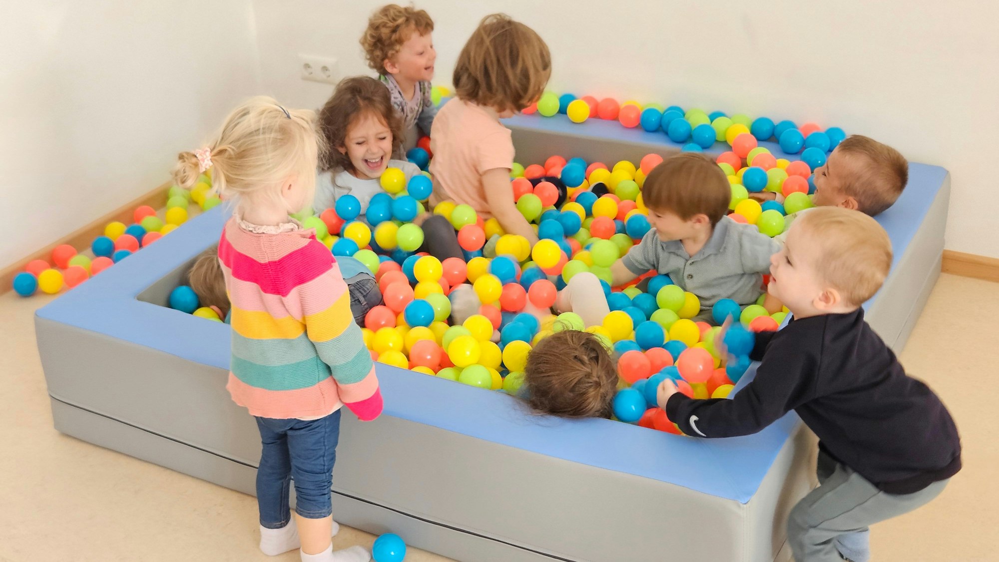 Mehrere Kinder toben in einem Bällebad.