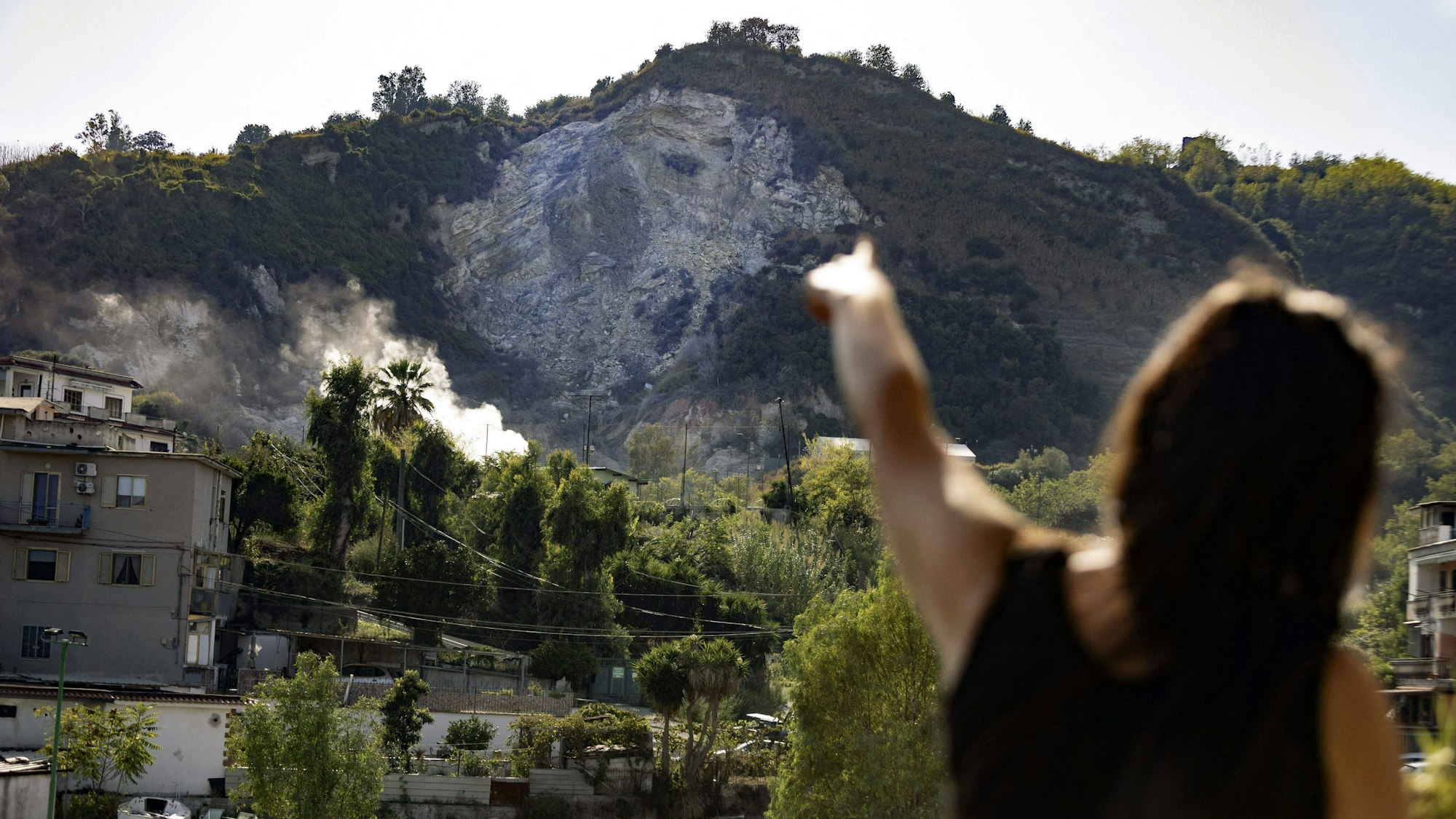 Eine Frau zeigt in Neapel in Richtung von Rauch, der über den Phlegräischen Feldern nahe der Stadt aufsteigt. Nach dem stärksten Erdbeben seit 40 Jahren steigen die Sorgen um einen Ausbruch von Europas Supervulkan.