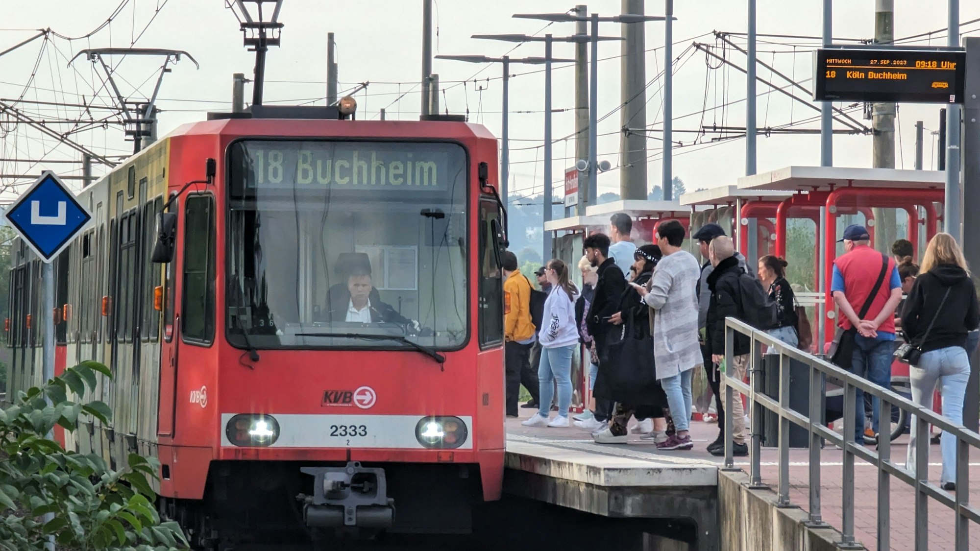 Das Foto zeigt Fahrgäste, die am Bahnsteig stehend, auf eine einfahrende Bahn warten.