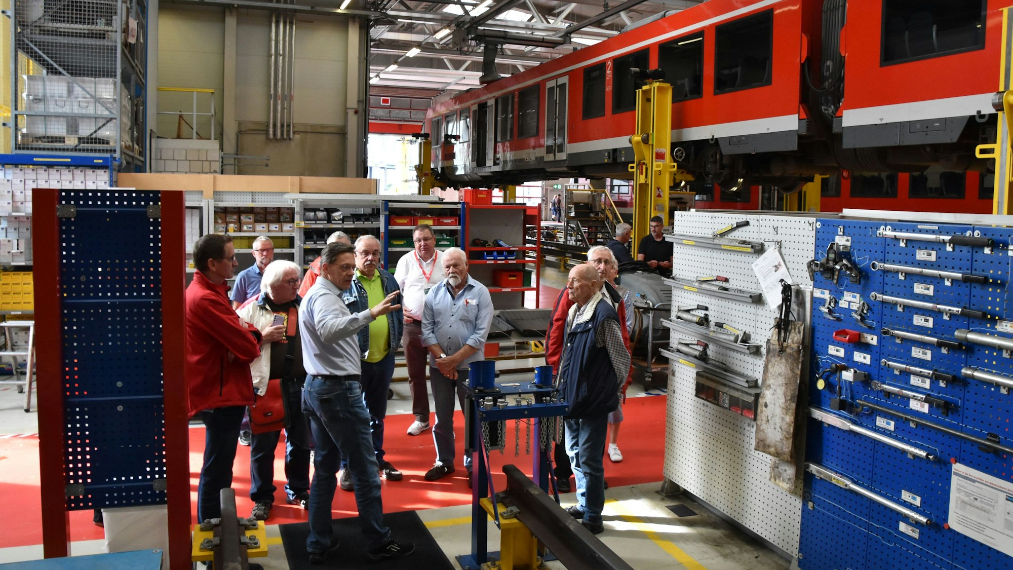 Ein Mann im blauen Hemd erklärt eine Wand mit zahlreichen Werkzeugen.