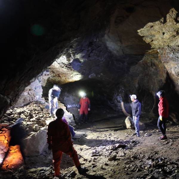 Mehrere Menschen mit Stirnleuchten stehen in einer Höhle.