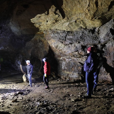 Mehrere Menschen mit Stirnleuchten stehen in einer Höhle.