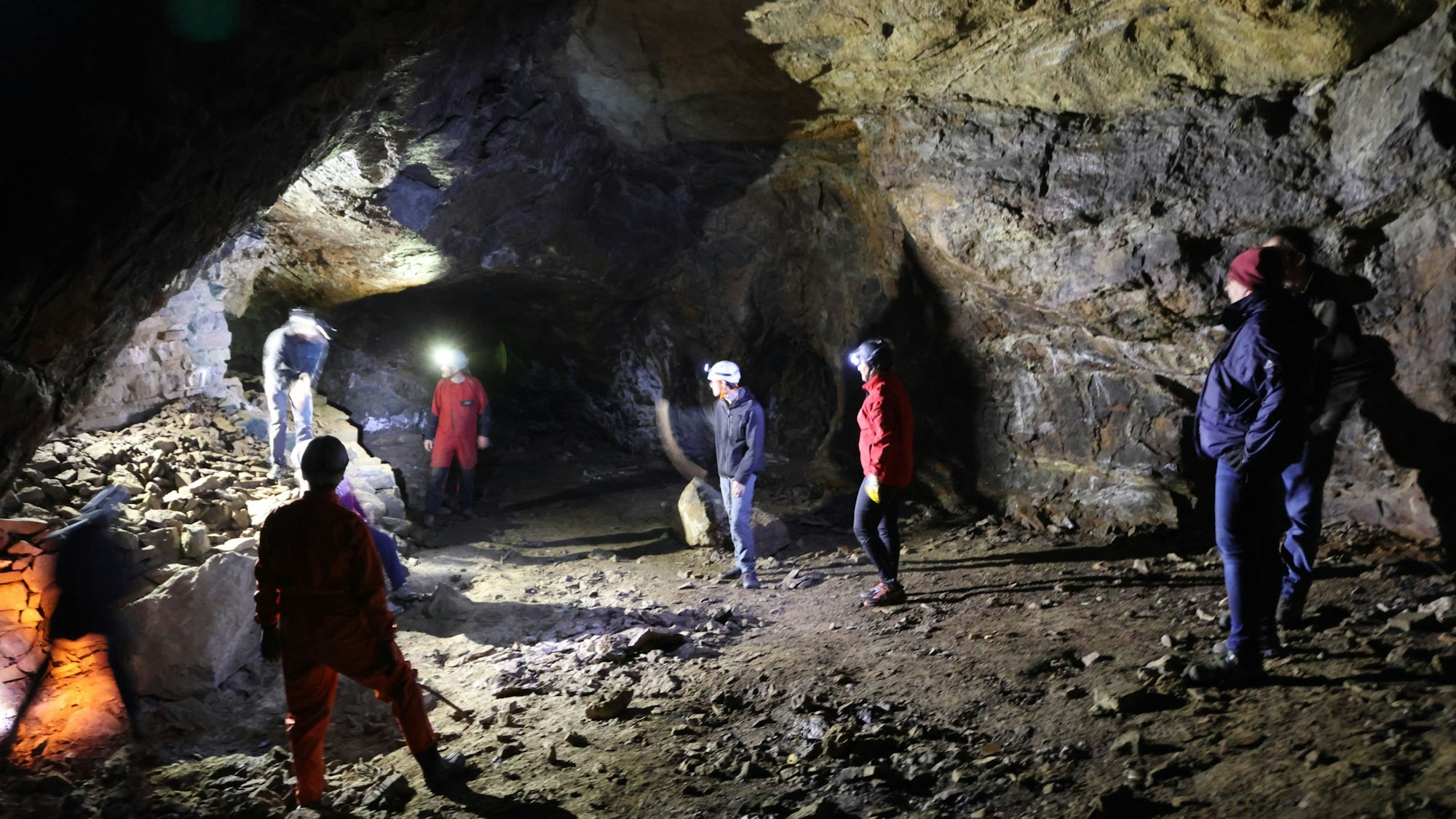 Mehrere Menschen mit Stirnleuchten stehen in einer Höhle.
