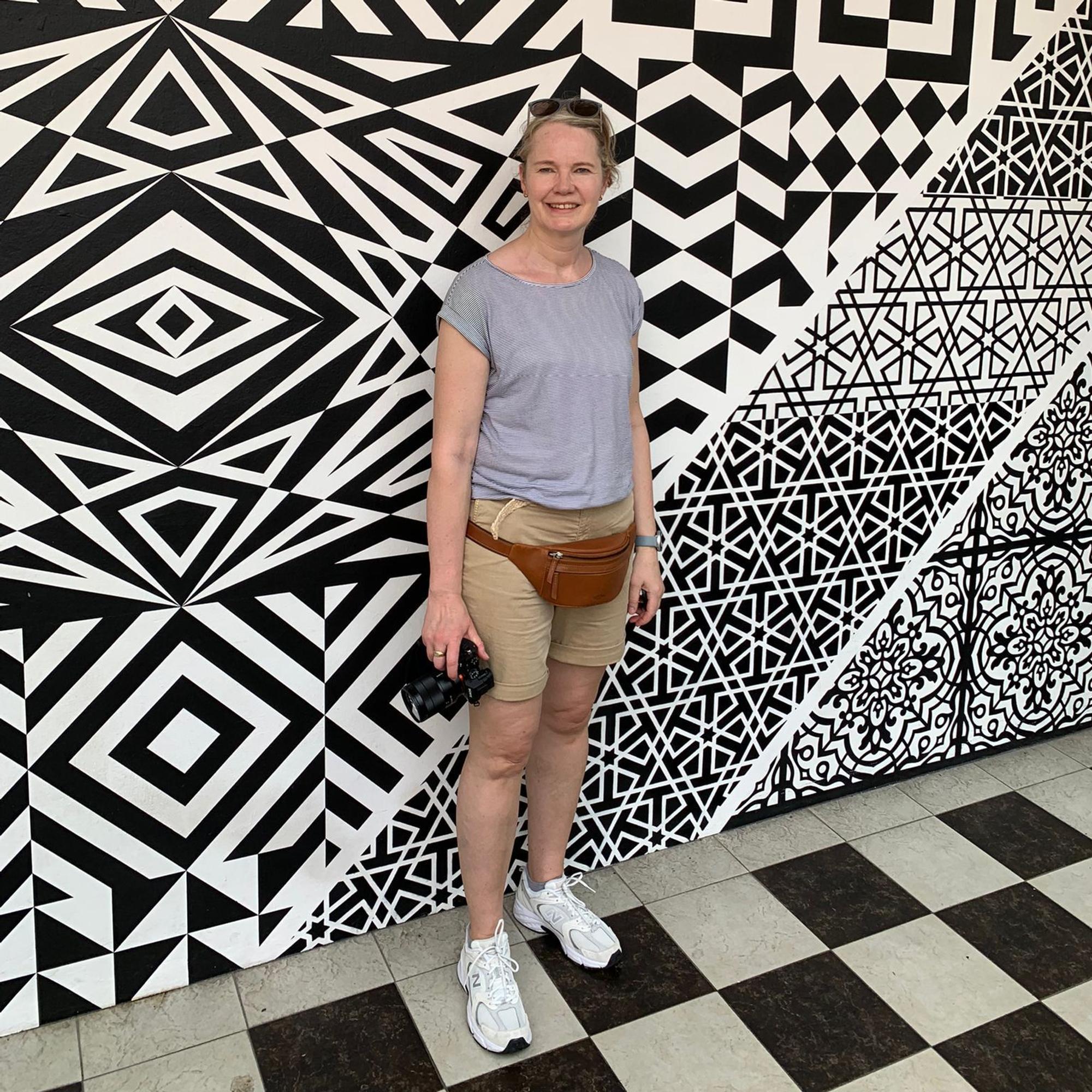 Kerstin von Berg steht vor einer gemusterten Wand.