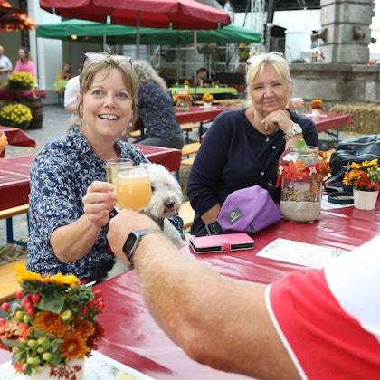 Eine Frau und ein Mann stoßen mit Saft- beziehungsweise Weingläsern an.