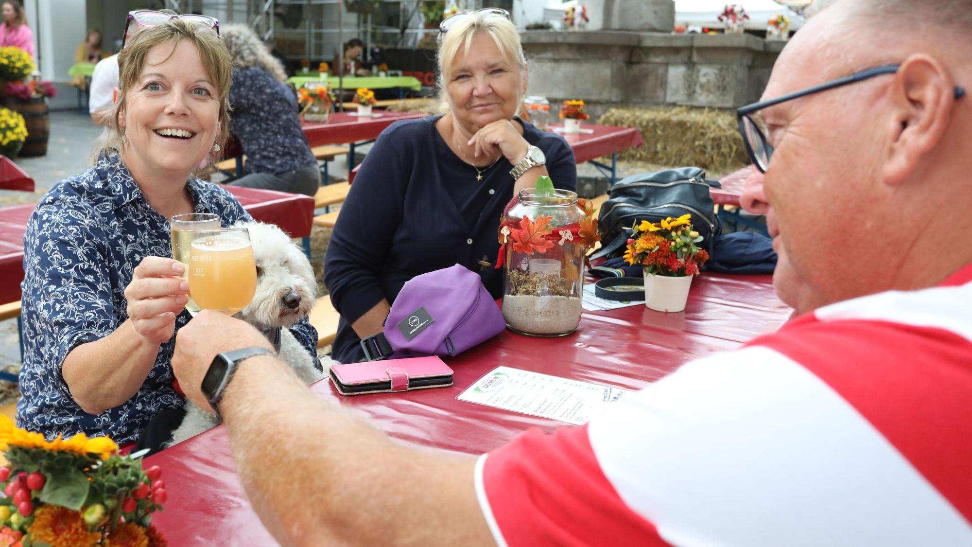 Eine Frau und ein Mann stoßen mit Saft- beziehungsweise Weingläsern an.