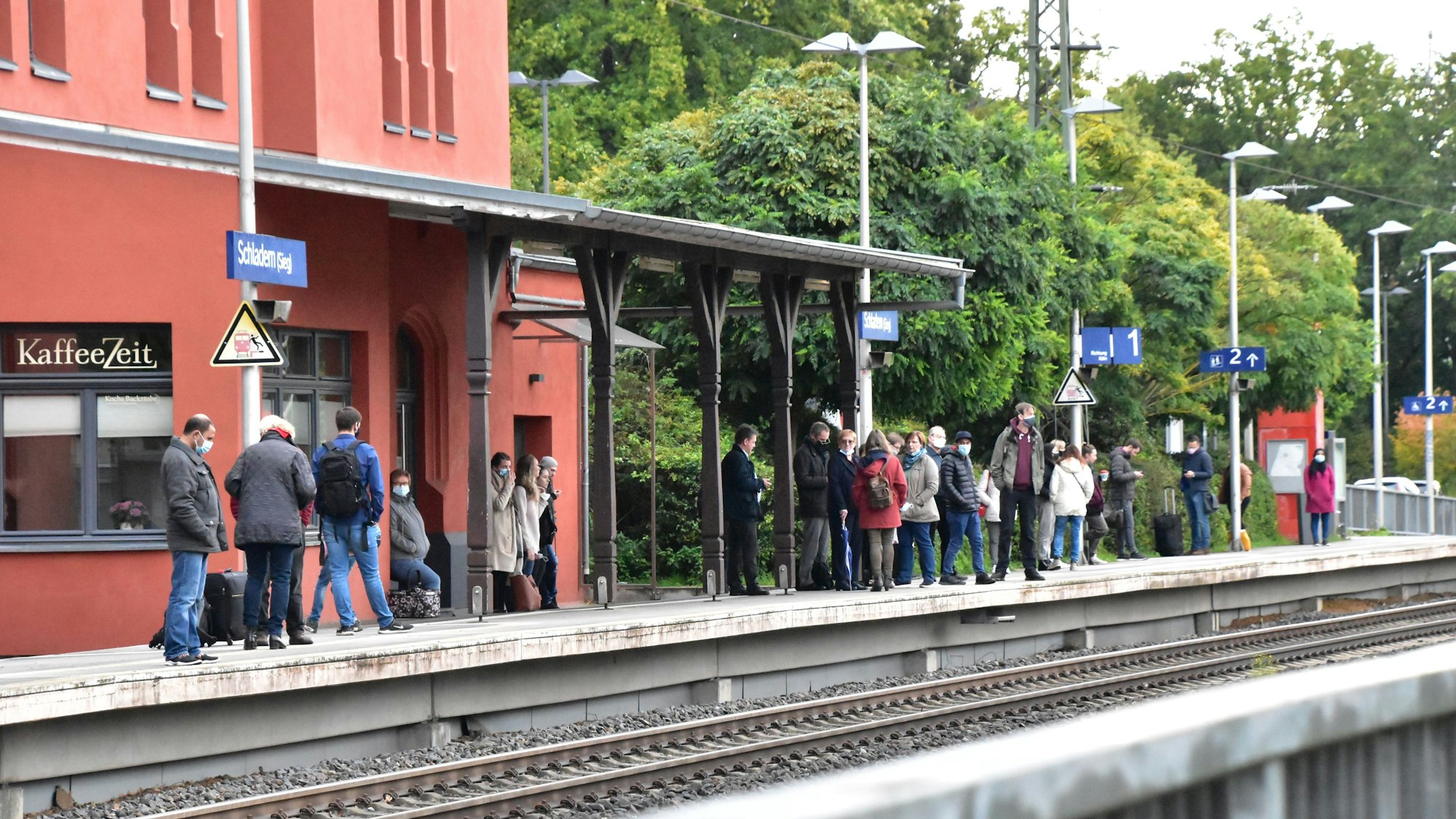 Reisende warten auf einem Bahnsteig auf den Zug.
