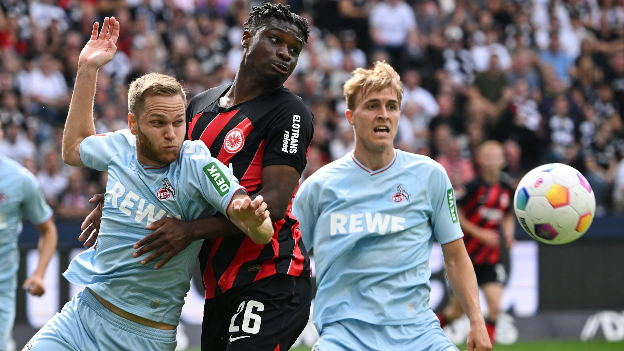 Frankfurts Omar Eric Junior Dina Ebimbe (M) und die Kölner Benno Schmitz (l) und Timo Hübers kämpfen um den Ball.
